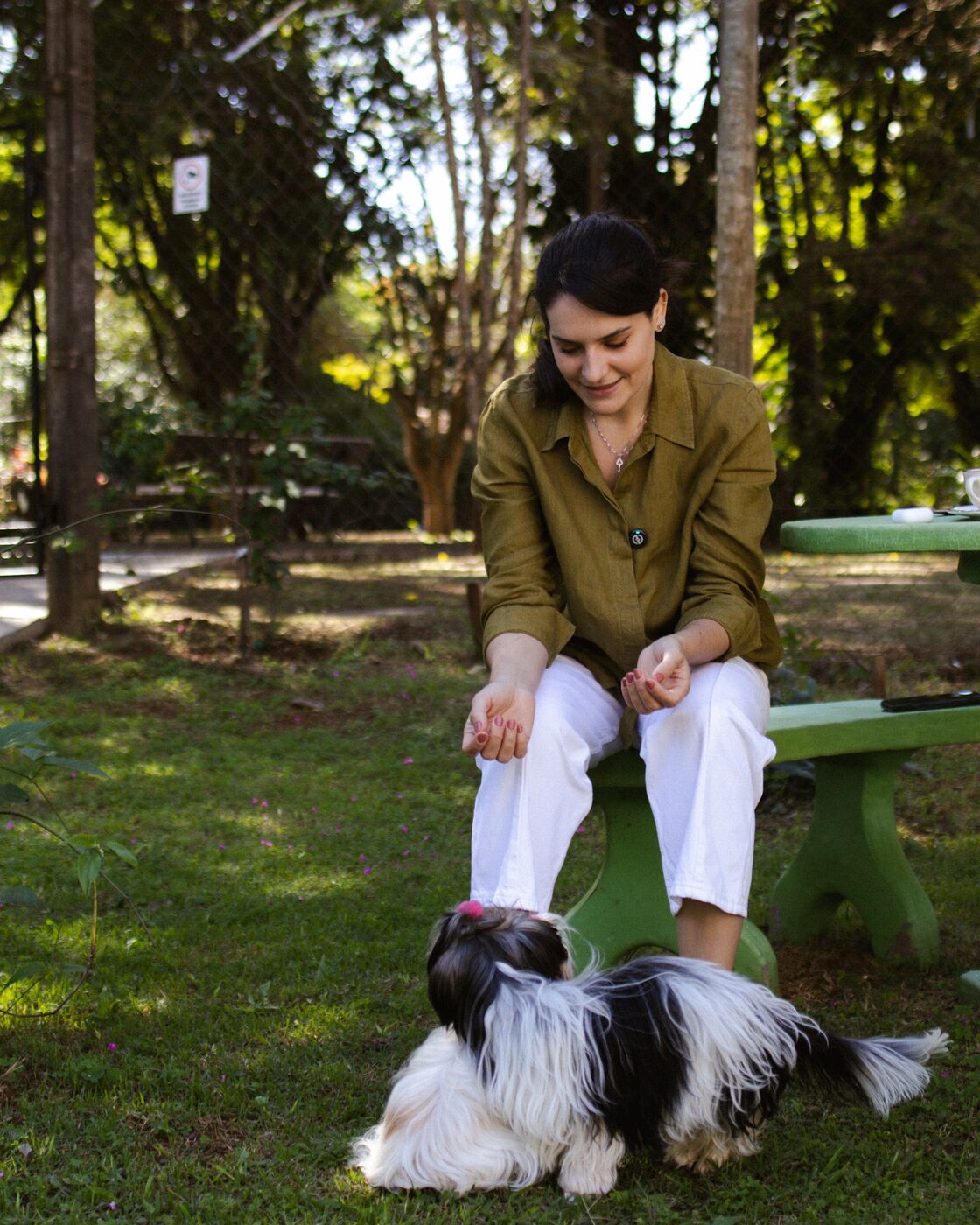 Mulher sentada no jardim brincando com um cachorro
