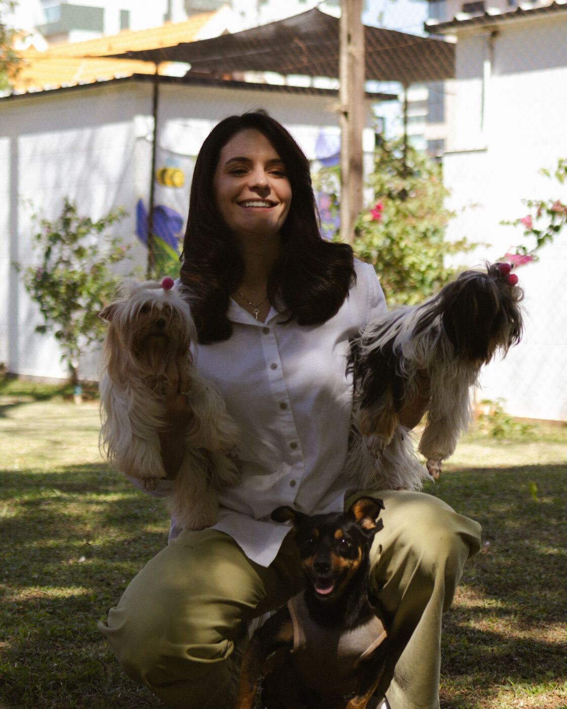 Mulher agachada no jardim com três cachorros