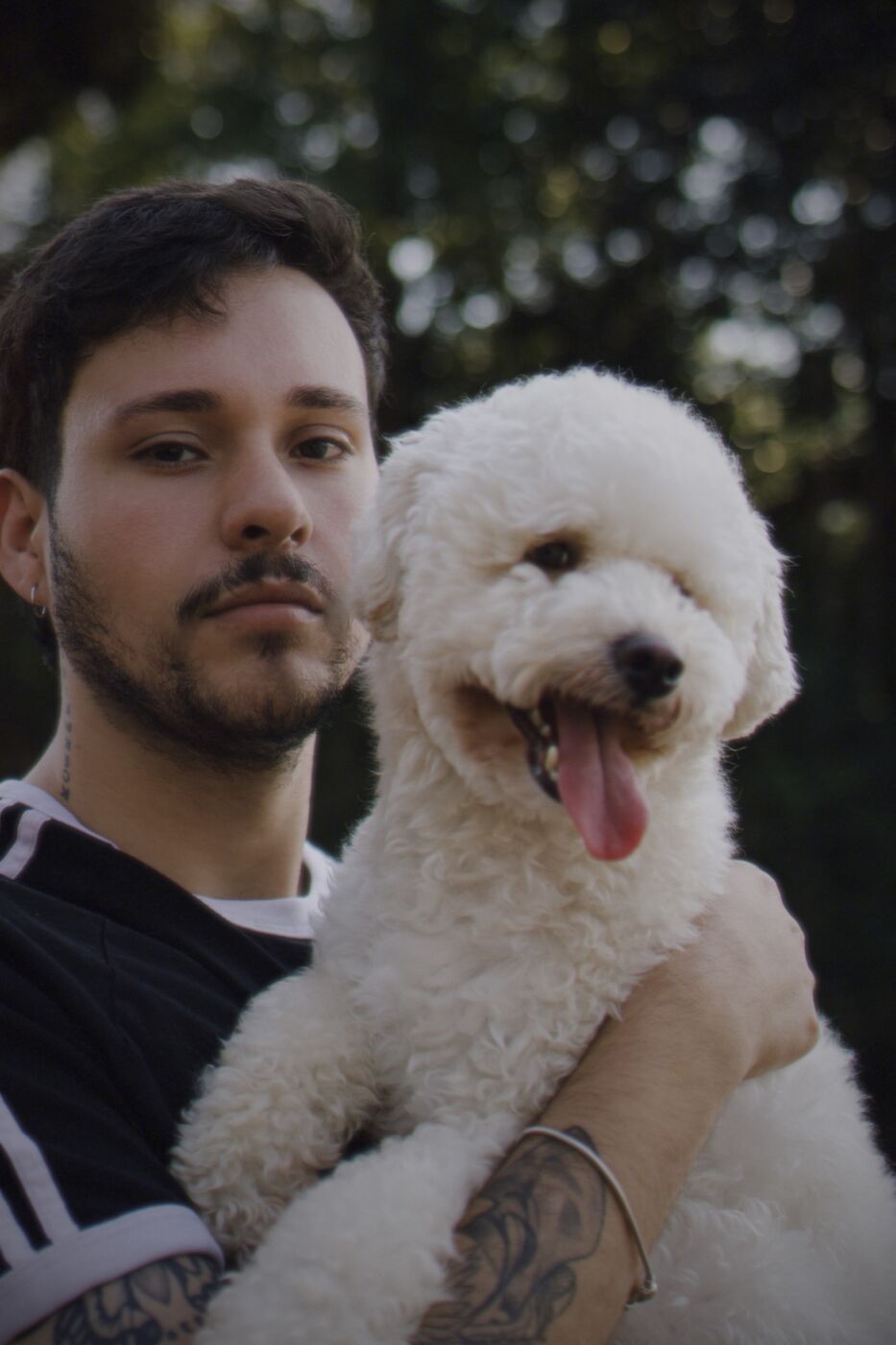 Homem com poodle de língua de fora, fundo escuro