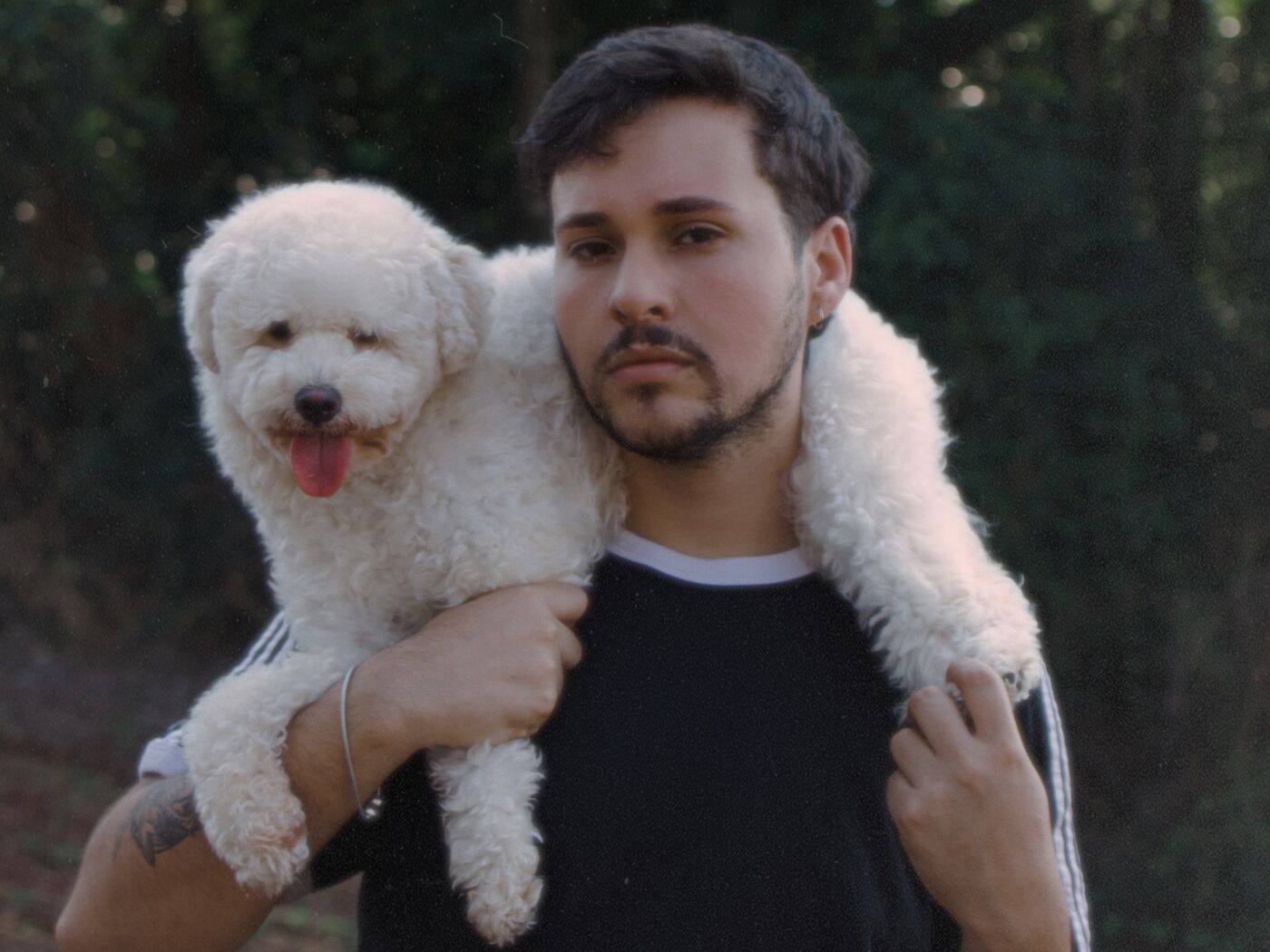 Homem com poodle nos ombros, fundo de mata