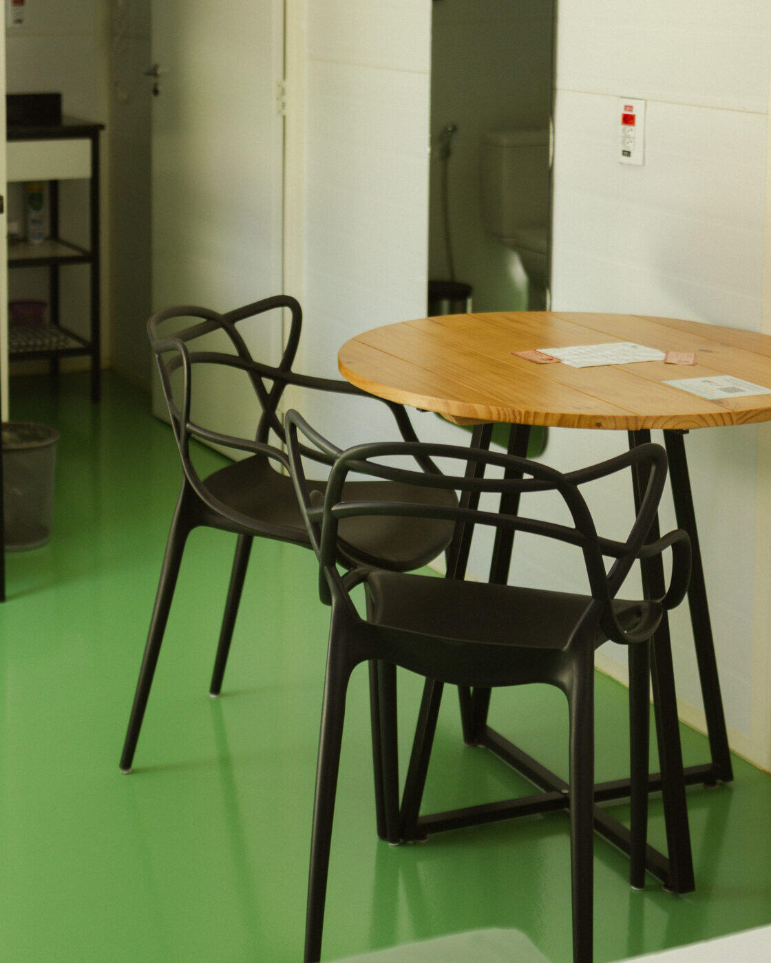 Mesa redonda e cadeiras pretas sobre piso verde
