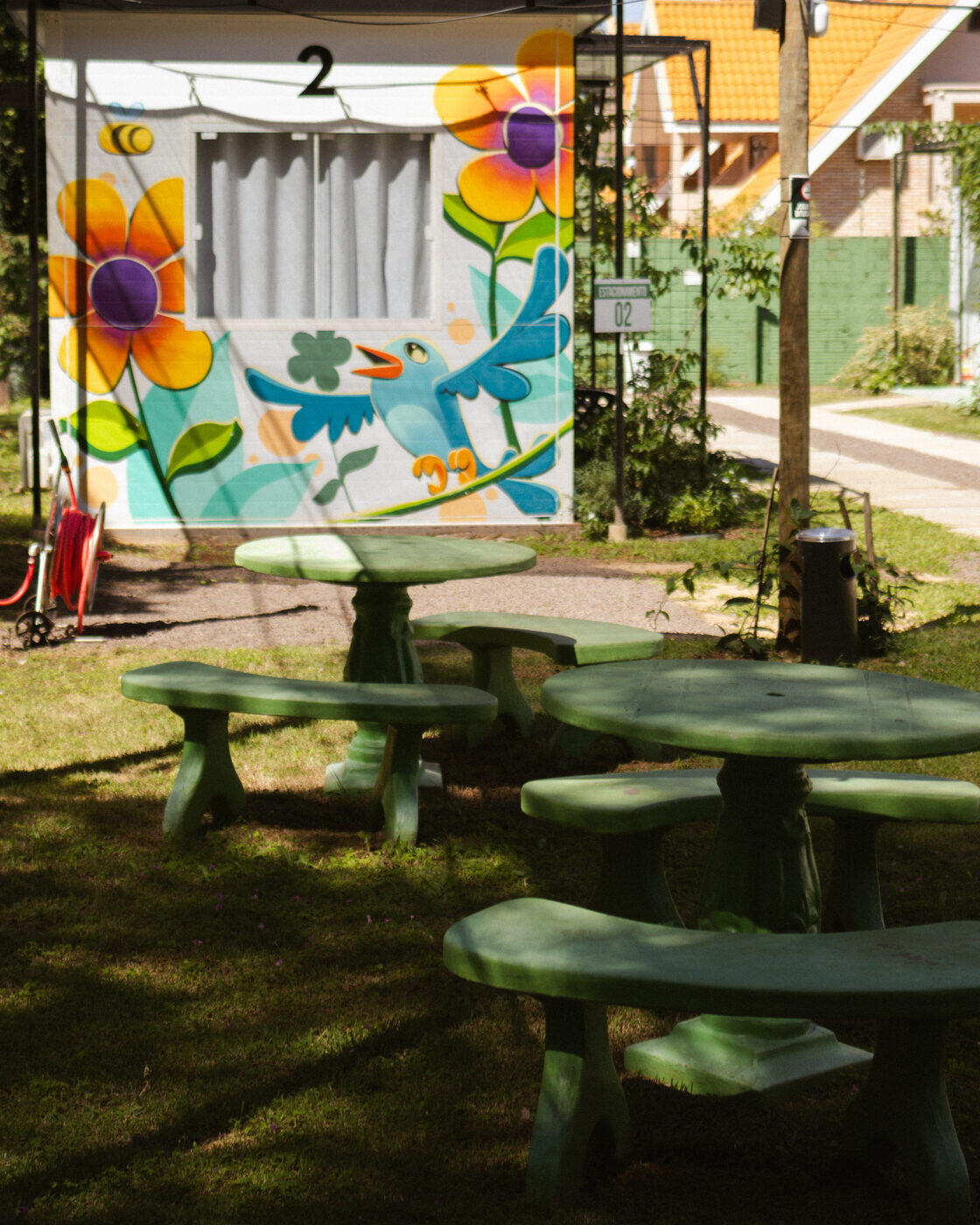 Mesas verdes de piquenique ao lado de container pintado